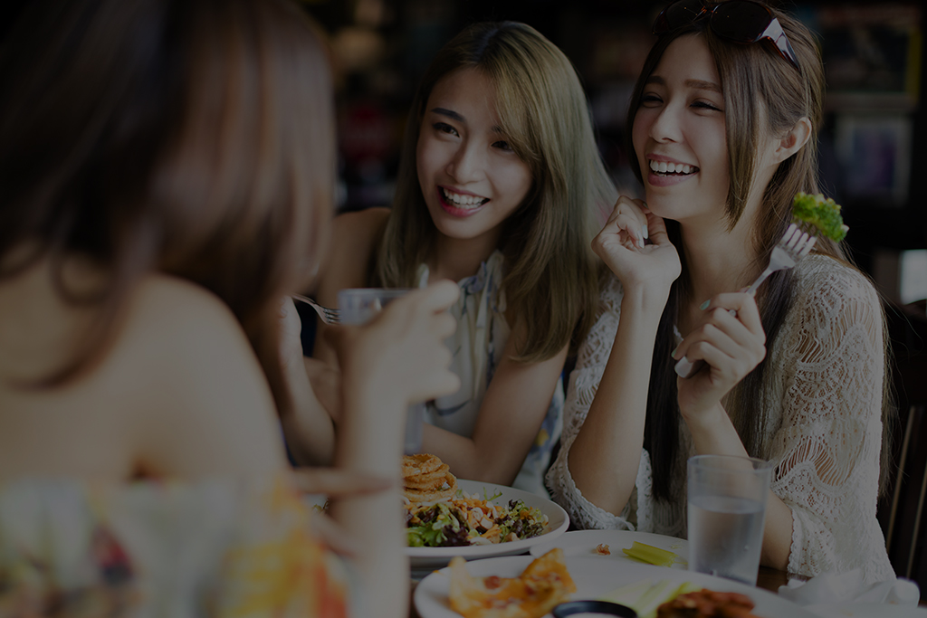 happy female friends sitting and chatting in restaurant